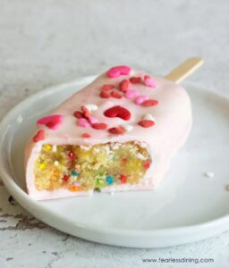 gluten free funfetti cakescicle with heart sprinkles on white plate
