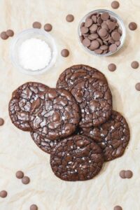 gluten free chocolate brownie cookies on parchment with sea salt and chocolate chips