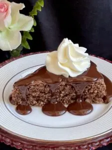 slice of gluten free hazelnut chocolate cake with fudge topping and whipped cream