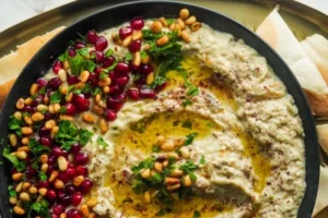 plant based superfood baba ghanoush in bowl topped with olive oil, pomegranate, and pine nuts