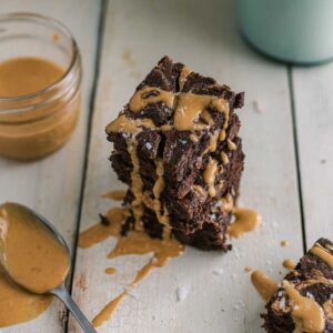 gluten free oat flour chocolate brownies stacked and drizzled with melted peanut butter