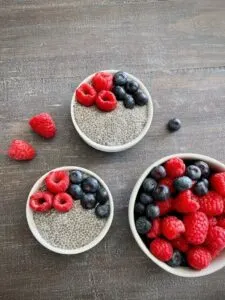 oat milk chia pudding topped with raspberries and blueberries on wooden boards
