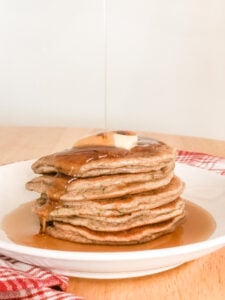 pouring maple syrup on top of zucchini protein pancakes