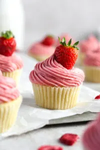 vanilla cupcakes with strawberry frosting and a fresh strawberry