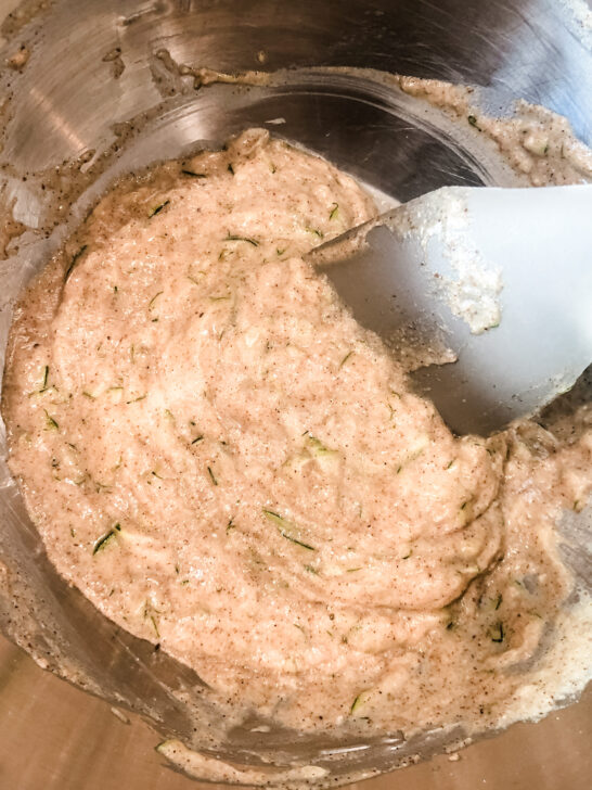 gluten free protein zucchini pancake batter in metal mixing bowl stirred with spatula