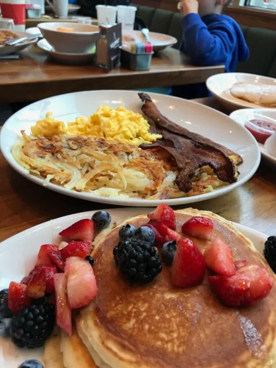 Breakfast from Wildberry Pancakes and Cafe with pancakes topped with berries, hashbrowns, bacon and eggs