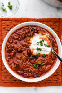 copycat instant pot wendys chili in bowl topped with sour cream and green onions