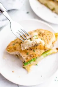 chicken stuffed with asparagus on plate with fork holding up a bite