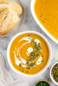 gluten free instant pot butternut squash soup topped with pepitas and side of gluten free baguettes