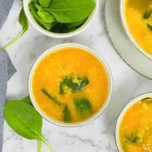 three bowls of instant pot quinoa soup with side of spinach