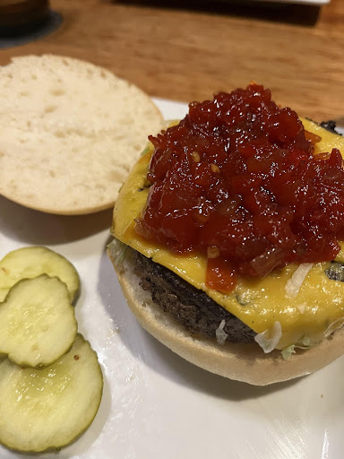 Burger with gluten free bun and vegan cheese and pepperjam with a side of pickles from Bruburger in Carmel