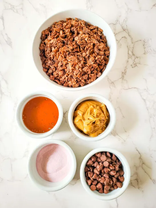 ingredients for nut-free protein bar recipe, cocoa rice, sunbutter, honey, strawberry protein powder, and chocolate chips