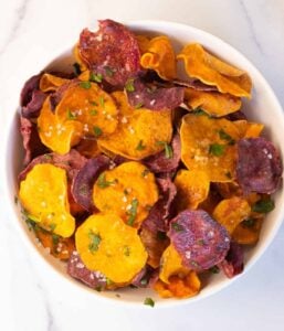 air fryer sweet potato chips in white bowl topped with salt and parsley