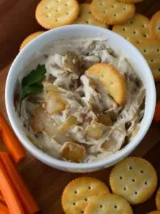 caramelized onion cashew dip in bowl with crackers and carrots