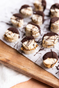 frozen banana bites stuffed with peanut butter and topped with chocolate on parchment