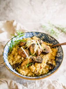 creamy mushroom quinoa risotto in blue and white bowl with gold rim on tea towel