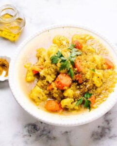 curried cauliflower quinoa soup with carrots in white bowl topped with parsley