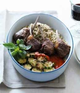 lamb chops with quinoa and zucchini in white and blue bowl on tea towel