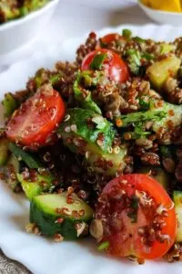 lentil quinoa salad with tomato and cucumber on white plate