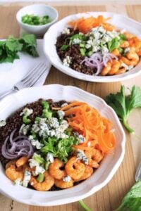 shrimp and quinoa bowls in white bowl on wooden board with fork