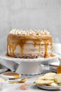 apple cider layer cake with caramel drizzle on white cake stand