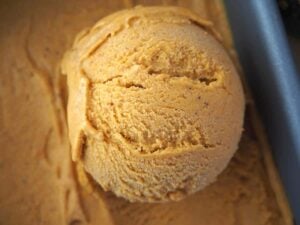 close up of scoop of pumpkin spice ice cream in pan
