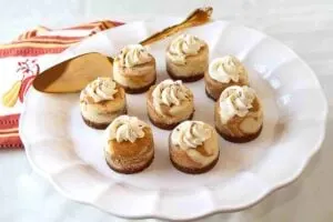 mini pumpkin cheesecakes arranged on white plate with pie server