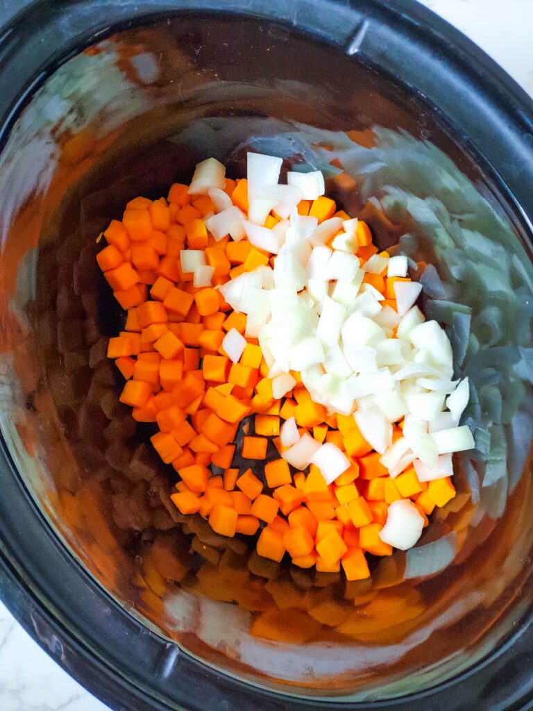 diced butternut squash and diced onion in a slow cooker insert
