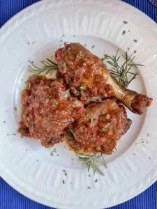 keto chicken cacciatore on white plate with rosemary
