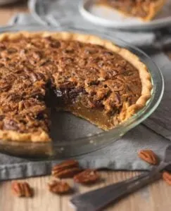 gluten free pecan pie in glass pie plate with slice cut out