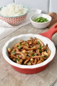 shimeji mushrooms in red bowl on cutting board