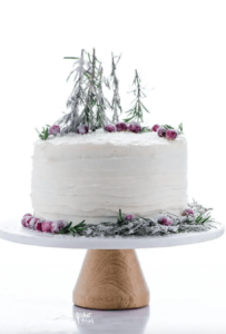 gluten free gingerbread cake on wood stand topped with sugared cranberries and rosemary trees