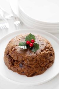 gluten free nut free christmas pudding on white plate topped with holly
