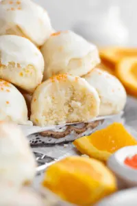 gluten free orange shortbread cookies stacked on plate with orange wedges