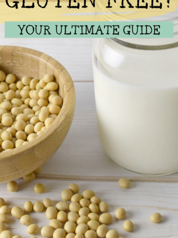 A photo of a wooden bowl filled with soy beans sitting beside a glass jar of soy milk on a wooden table with the text overlay 'Is Soy Gluten Free? Your Ultimate Guide'