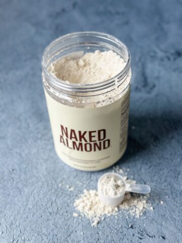open tub of naked almond vegan gluten free protein powder with scoop of protein