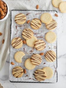 dairy free almond flour shortbread cookies drizzled with chocolate on a cooling rack with parchment