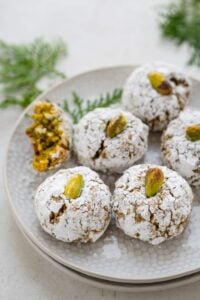 gluten free Italian pistachio cookies on white plate with greenery