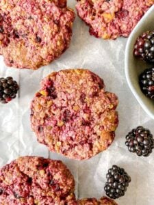 gluten free dairy free blackberry oatmeal cookies on parchment with fresh blackberries
