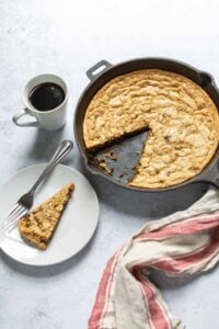 gluten free dairy free chocolate chip skillet cookie with slice cut out and cup of coffee