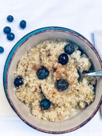gluten free breakfast quinoa in bowl topped with fresh blueberries