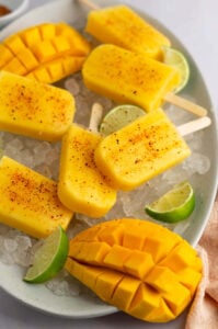 homemade mango popsicles on ice with lime wedges
