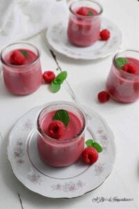 homemade raspberry panna cotta in glass parfait cups on saucers