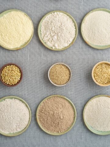 bowls of gluten free flours and gluten free grains on gray background