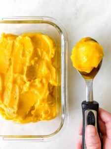 homemade mango sorbet in glass dish with ice cream scoop