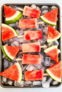homemade watermelon popsicles on ice with slices of watermelon