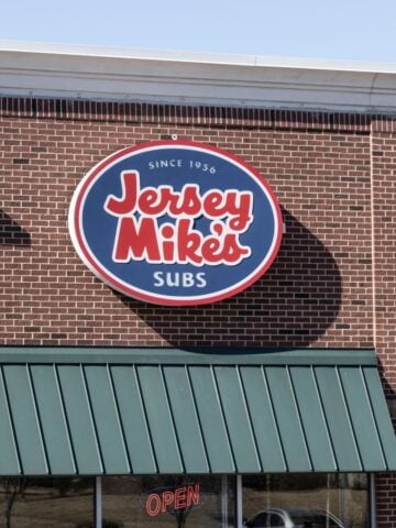 The exterior of a Jersey Mike's restaurant with an Open sign in the window