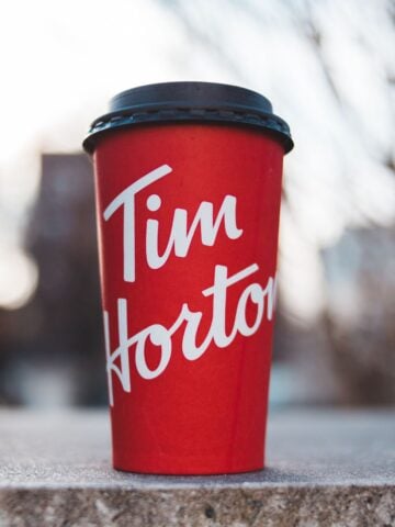 A close-up of a large, red Tim Hortons coffee cup with a lid