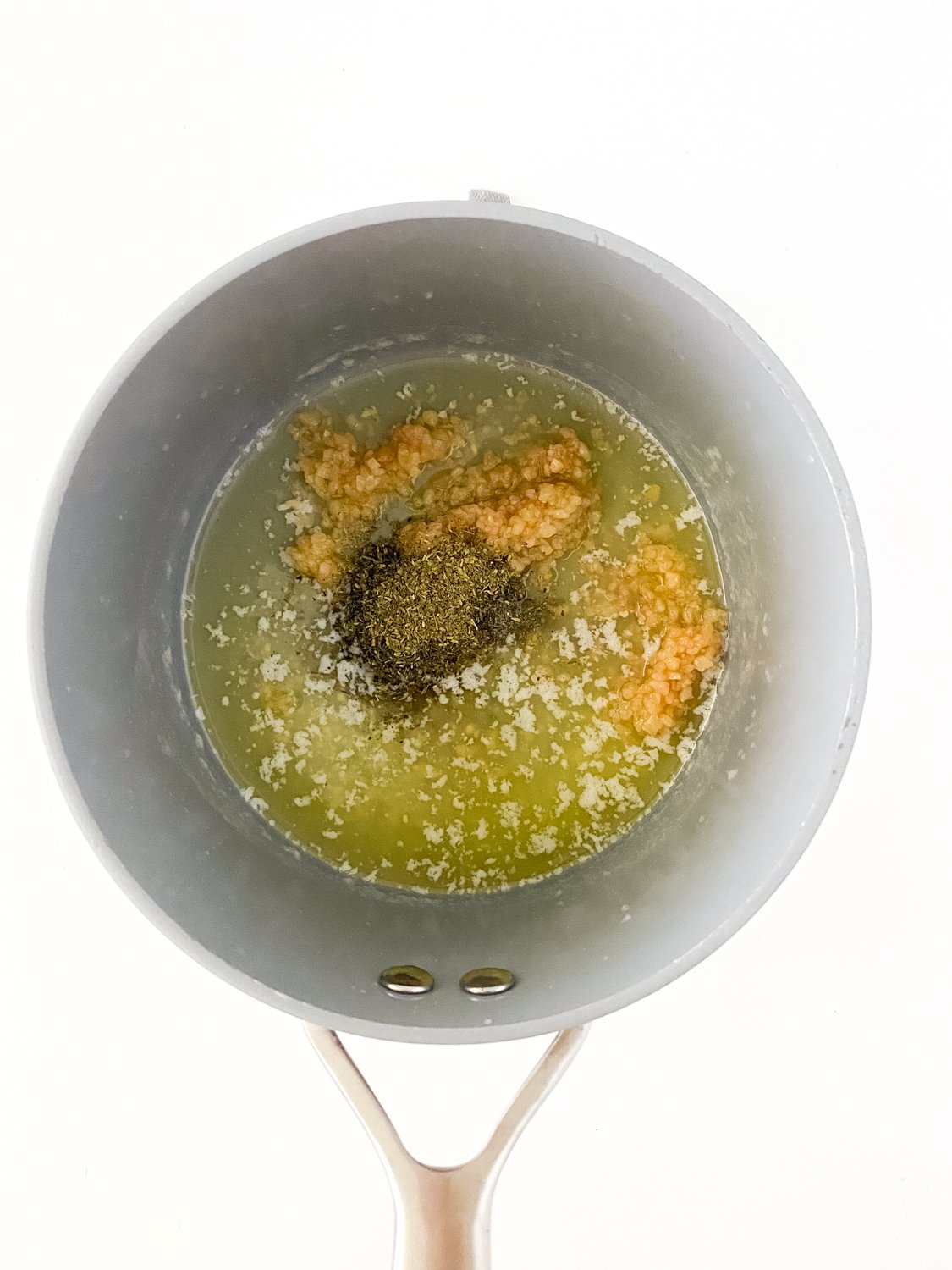 Looking down into a pot containing melted butter and seasonings for gluten free garlic parmesan sauce