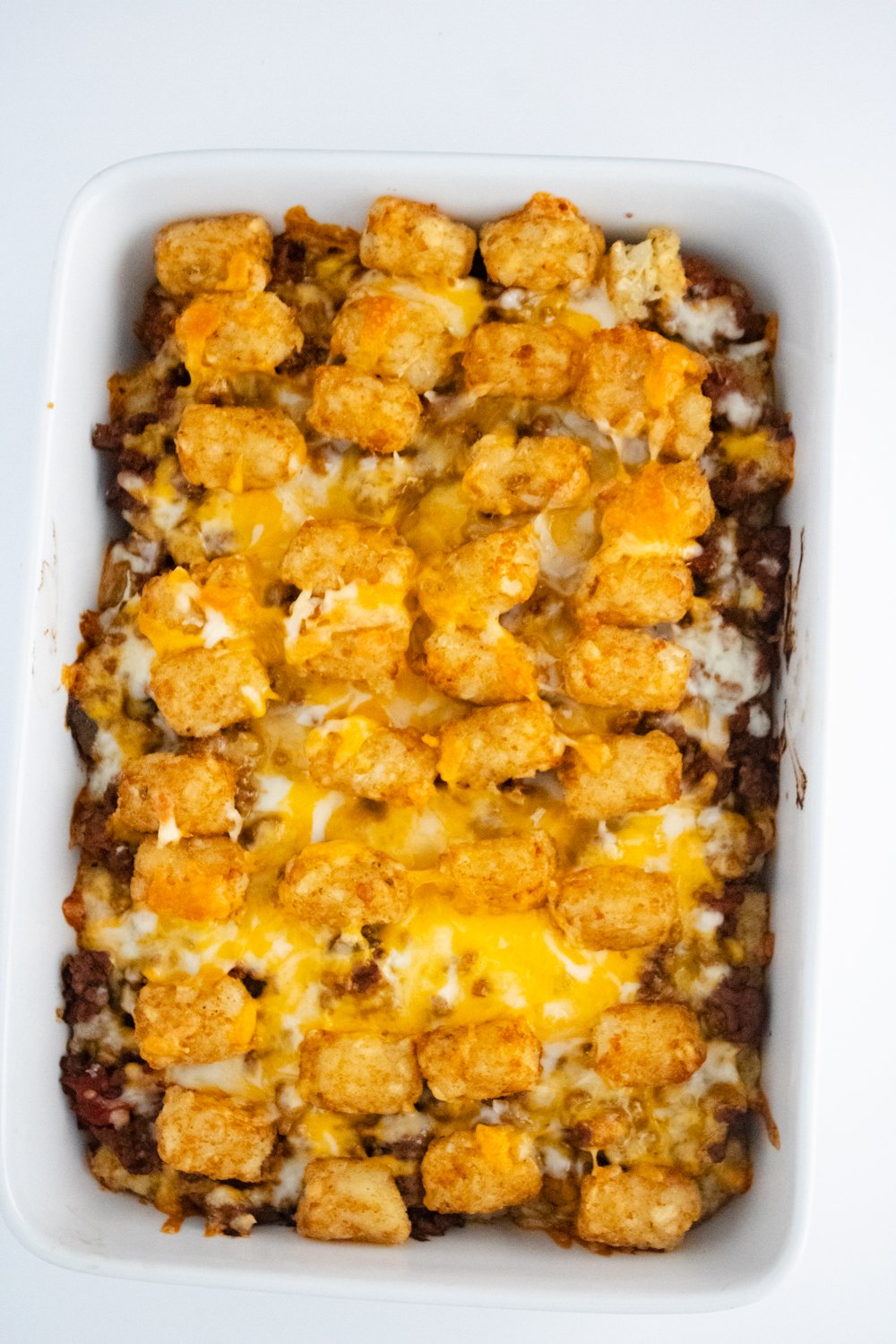 A close up of the casserole dish showing tater tot casserole after it comes out of the oven with melted cheese.
